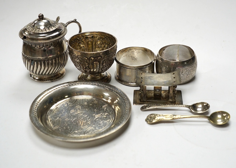 Sundry small silver including five silver napkin rings, and 800 napkin ring, a Victorian silver mustard and salt, an Egyptian small white metal dish, three silver condiment spoons and five plated items. Condition - poor